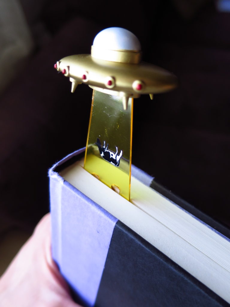 Separador de libros de platillo volador abduciendo una vaca.