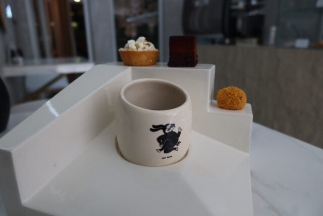 Taza del ritual del café 2025 en "Pizca Patisseri" junto con tres postres: pan de maíz, brownie de ramon y trufa de ajonjolí