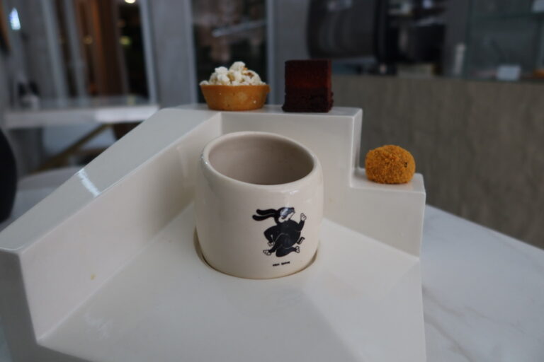 Taza del ritual del café 2025 en "Pizca Patisseri" junto con tres postres: pan de maíz, brownie de ramon y trufa de ajonjolí